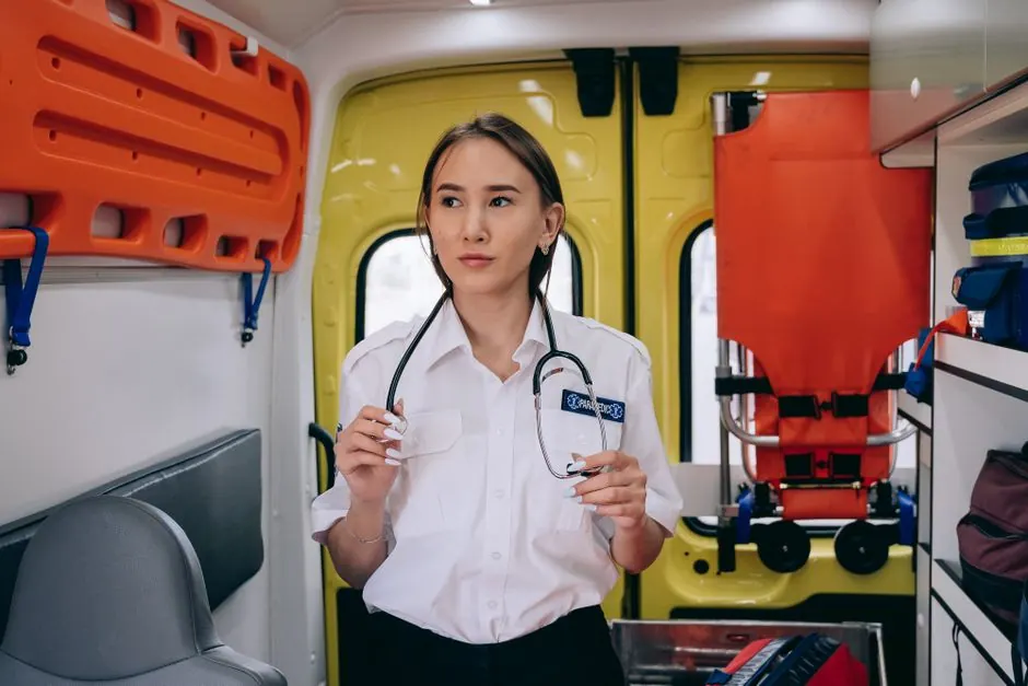 Portrait of a female paramedic holding a stethoscope inside an ambulance.
